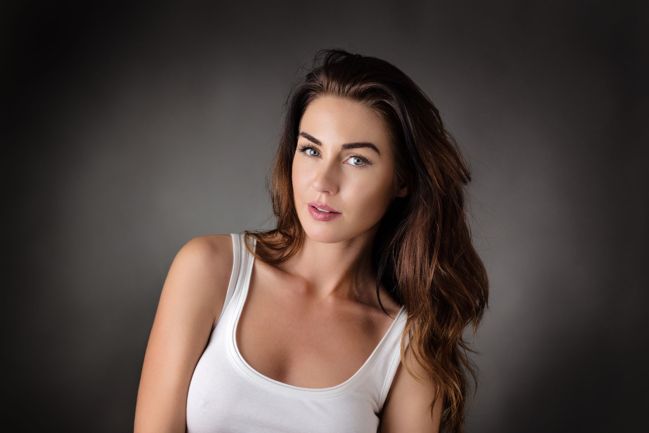 Woman with dark hair in a white tank top.